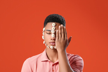 Portrait of handsome young man with flowers on face against color background