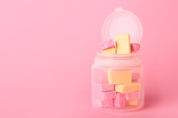 Jar with tasty chewing gums on color background