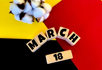 March 18 on wooden cubes on a multi-colored background of yellow, red and black.next to cotton .Spring.Calendar for March .