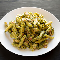 Homemade One-Pot Chicken Spinach Bacon Alfredo Pasta on a plate on a black surface, side view.