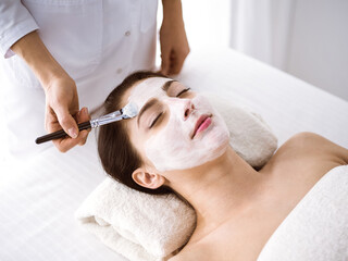 Obraz na płótnie Canvas Beautiful brunette woman enjoying applying cosmetic mask comfortable and bissfulle. Relaxing treatment in medicine and spa center concepts