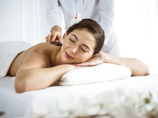 Fototapeta na wymiar Beautiful brunette woman enjoying back massage comfortable and blissful. Spa and medicine concept