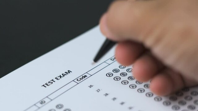 Education and exam concept. Answering multiple-choice test questions. A student filling out test sheet. Student hand with pen fill in exam test answer sheet. Answering test questions on the exam