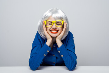 emotional Woman in a White wig yellow glasses red lips Glamor cosmetics sitting at the table