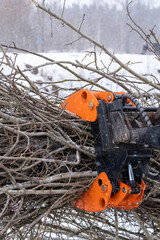 small stand-on mini skid steer with grapple full of wooden branches