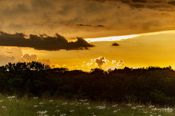 Thunderstorm clouds over a rural landscape at sunset