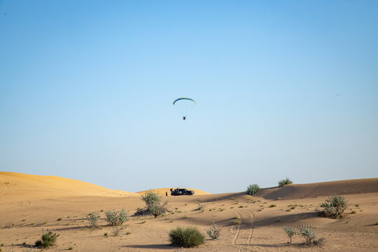 Para plane flying over sandy dunes on background of the clear blue sky