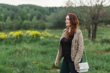 Young woman enjoying blooming spring in a forest walking. Green grass and yellow flowers in the meadow