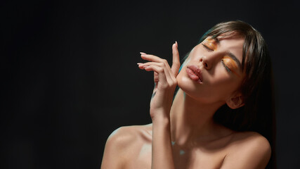 Beauty portrait of young brunette woman with healthy brown hair and professional orange makeup...