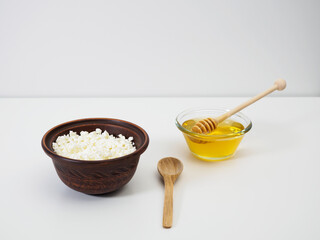 Healthy breakfast or snack of fresh homemade cottage cheese in a clay bowl and natural flower honey on a white background