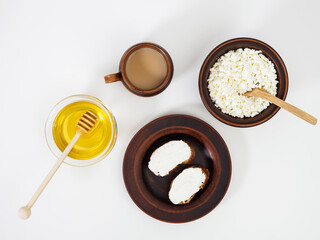 Delicious healthy breakfast with farm cottage cheese, toasts with soft curd cheese, a cup of coffee and honey on a white plate. Lunch in handmade earthenware. Pottery. Flat lay, top view