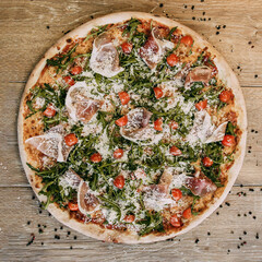 Pizza with bacon arugula and tomatoes. Top down view on delicious single round pizza with arugula lettuce and bacon meat toppings