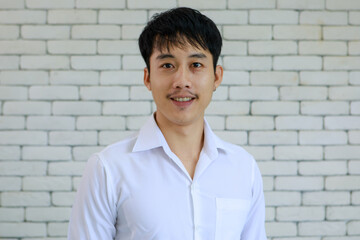 Portrait of young and handsome Asian man with beard pose smile and happy friendly face on white brick wall background