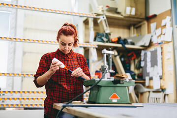 Woman worker putting glue to stick wooden frame