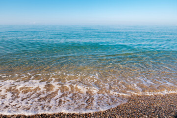 Moving calm waves on the beach. blue surf of the morning sea with haze above its surface. Morning sea depthlessness background