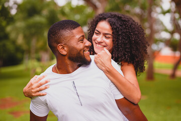afro brazilian couple together embracing in a park enjoying a late afternoon, loving each other and...