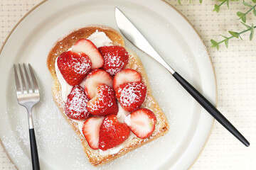 Strawberry cream toast on a round plate. With a modern knife and fork.