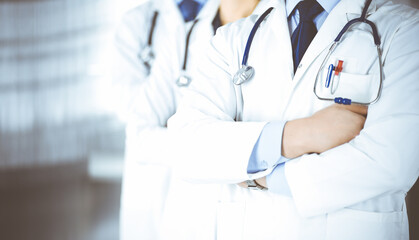 Group of modern doctors standing as a team with crossed arms and stethoscopes in hospital office. Physicians ready to examine and help patients. Medical help, insurance in health care, best desease