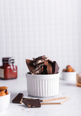selective focus. pieces of milk and bitter chocolate in a ceramic white cup on a light background
