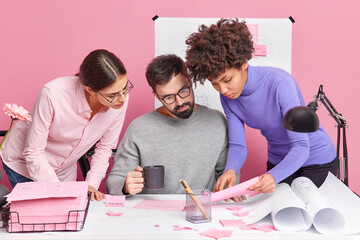 Three diverse colleague collaborate and have brainstorming meeting look attentively at papers pose...