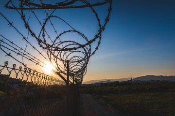 Barbed wire with spiral blades, to protect a private property outside, with the light of the sunset...