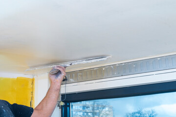 Hand of builder worker  spacks ceiling with putty plaster aligning ceiling  with spatula. ...