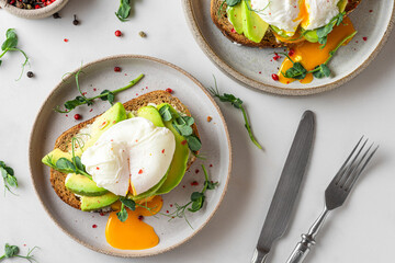Healthy breakfast. Whole wheat toasted bread with avocado, poached egg, soft cheese and sprouts on white background