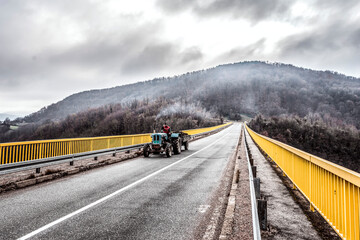 Farmer driving a tractor through the bridge in Serbia with mountains on a background