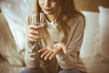 Close-up woman holding pills time to take medications, cure for headache, high blood pressure or cholesterol level remedy pain killer drugs. Stay at home concept during Coronavirus pandemic and self