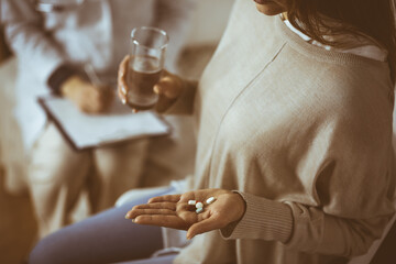 Close-up woman-patient holding pills near her doctor, time to take medications, cure for headache or remedy pain killer drugs. Stay at home concept during Coronavirus pandemic and self isolation