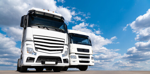 Obraz na płótnie Canvas Two white trucks against the blue sky