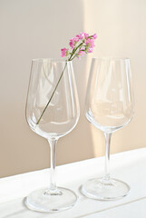 pink flower in a wine glass. two glasses on a white wooden table. garden party. wedding or anniversary selebration. birthday drinks, holiday and vacation concept