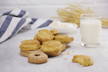 Cookies on a wooden board with a glass of milk on a light table, kitchen