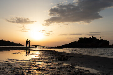 Couple's silhouette at the beach photoshooting the sunset