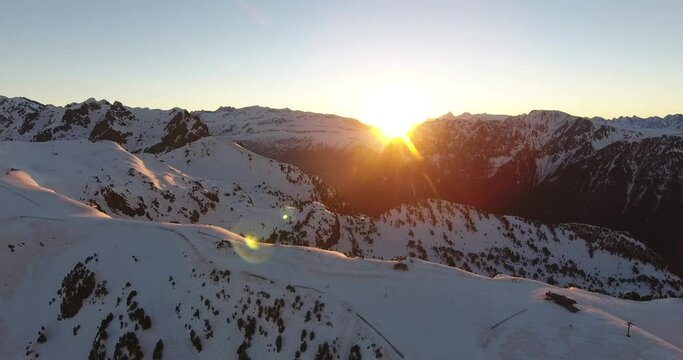 Chamrousse French Alpine peaks with sun rising above mountain ridge, Aerial dolly right shot
