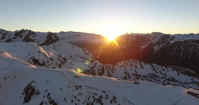 Tall Chamrousse Alpine peaks in France with bright sunrise above mountain ridge, Aerial dolly out