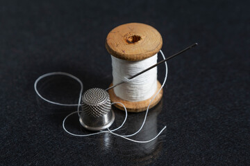 needle and thread with thimble on black