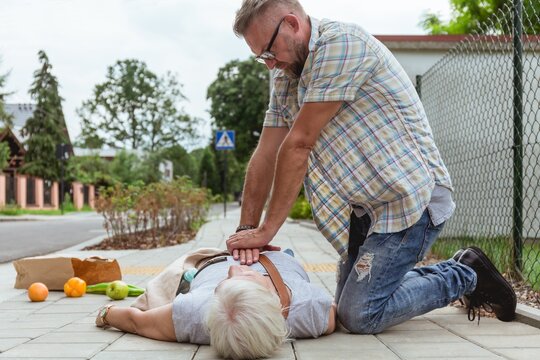 Man performs a heart massage on an senior lady who fainted on the street