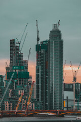 Fototapeta na wymiar London UK February 2021 Massive skyscrapers beign built on the West part of london, seen from the city center. Many contruction cranes rising above the clouds and above the river Thames