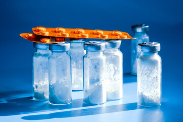 Medical bottles for injection with white powder and drug blister packs. Science and pharmacy concept