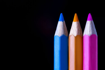 a row of colored pencils on a black background
