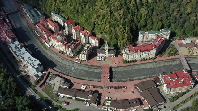 Rosa Khutor resort of Sochi, city hall, pedestrian bridge, Rathaus and central square view at sunny day. Roza Khutor. Mountains. Sunny day. Hotels. River Mzymta. Krasnaya polyana. 