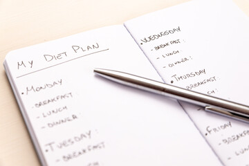Diet plan: planning of the weekly diet, with the foods to eat during the week, written on a white notebook with black ink.