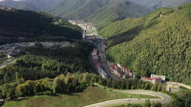Rosa Khutor resort of Sochi, city hall, pedestrian bridge, Rathaus and central square view at sunny day. Roza Khutor. Mountains. Sunny day. Hotels. River Mzymta. Krasnaya polyana. 