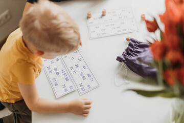 
Boy 2 years old blond sitting at the table playing lotto