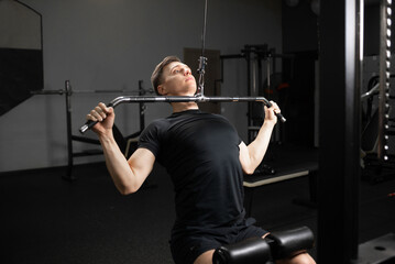 Handsome young man doing bench press, arm and chest trainer. The process of preparing for a powerlifting competition.