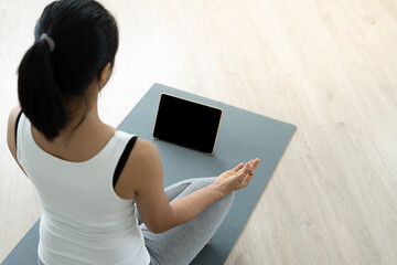 Women wearing exercise clothes yoga sitting posture calm relax at home. Women learn yoga online through a tablet. Healthy lifestyle ideas