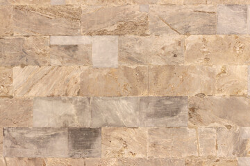 The surface of the wall of the building, made of hewn marble blocks of different sizes and colors.