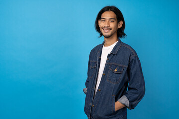 A long-haired young Asian man wearing a white T-shirt smile with a blue background. Asian man so cool and smartconcept