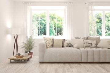 Fototapeta premium White living room with sofa and summer landscape in window. Scandinavian interior design. 3D illustration
